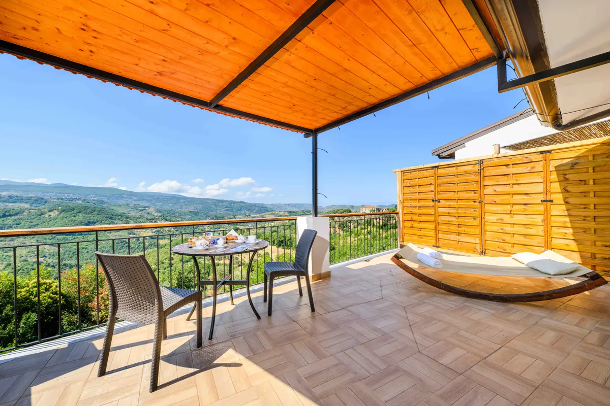 Covered terrace with a small table, hammock and a view of the hills
