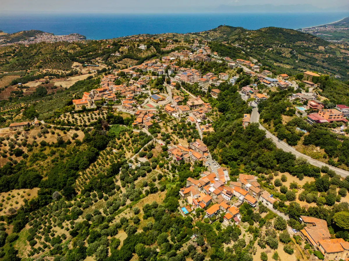 Aerial view of the village of Ogliastro Cilento, with Ca' del Borgo and its pool and the sea on the horizon
