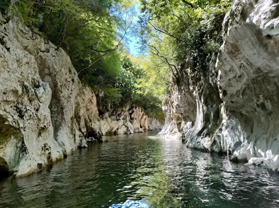 The Calore river flowing between white rock walls and the woods of the Gole del Calore